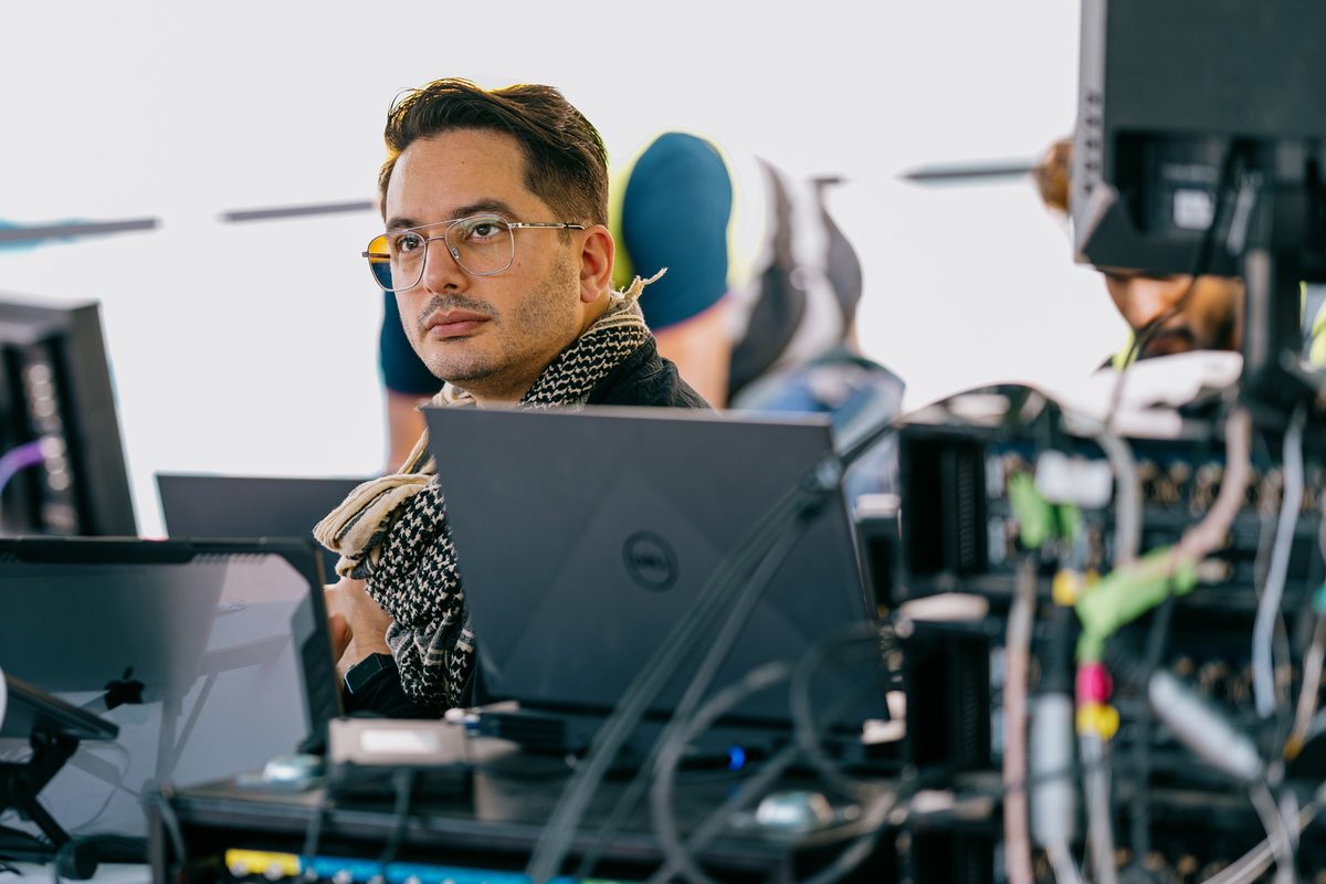 Ben at the production desk, behind laptops and a rack of cabling